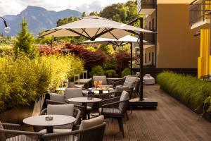 a patio with tables and chairs and an umbrella at Hotel Posta in Comano Terme