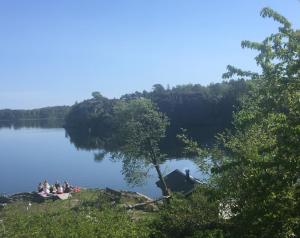 a group of people sitting on the shore of a lake at Slussens Stay in Henån