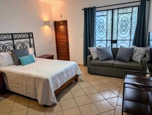 a bedroom with a bed and a couch and a window at Casa Kiiwik - Luxury Property with a Private Outdoor Pool and Parking in Central Merida in Mérida +46 photos