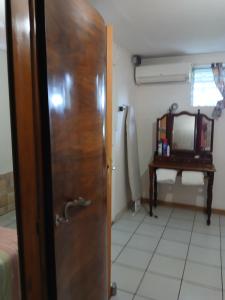 Una puerta que conduce a un dormitorio con una mesa y un espejo. en La maison du bonheur, en Fort-de-France