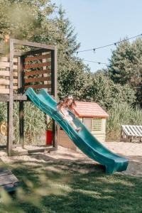 a girl on a slide at a playground at Przystanek Roztocze- leśne SPA, Jacuzzi & sauna in Susiec +55 photos