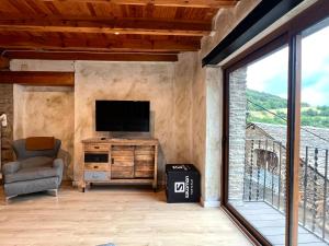 a living room with a television and a chair at Casa Sinera - L'Amfitriona in Roní +17 photos
