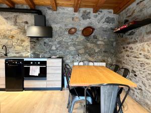 a kitchen with a wooden table and a stone wall at Casa Sinera - L'Amfitriona in Roní