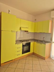 a yellow kitchen with yellow cabinets and a sink at Casa al mare 2 in Rosignano Solvay