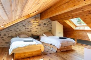 zwei Betten in einem Zimmer mit Holzdecken in der Unterkunft La Grande Maison Rouge in Angoustrine