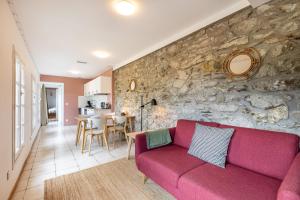 ein Wohnzimmer mit einem roten Sofa und einer Steinmauer in der Unterkunft La Grande Maison Rouge in Angoustrine