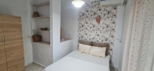 a small bedroom with a white bed and a wall at Appartement s1 hamamet in Hammamet