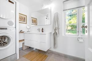 a white bathroom with a sink and a washing machine at 3331-Stege-Raby-Sovej-1 in Stege +45 photos