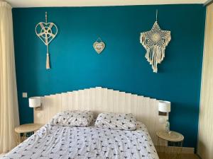 Un dormitorio con una pared azul con una cama y decoraciones. en F2 vue mer dans résidence avec piscine, en Ajaccio 14 fotos más