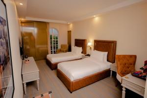 Una habitación de hotel con dos camas y un escritorio. en Cityscape Rooms & Suites, en Islamabad