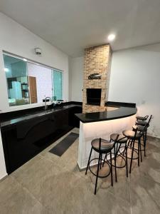 a kitchen with a bar with stools and a sink at Casa com piscina, 700M da praia in Peruíbe