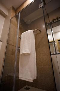 Una ducha con una toalla blanca sobre una puerta de ducha de cristal. en Cityscape Rooms & Suites, en Islamabad