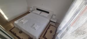 a small bedroom with a white bed and a window at Apartman Ivan in Tomislavgrad