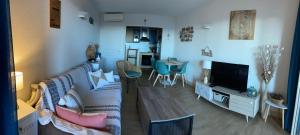 Una sala de estar con un sofá y un televisor. en F2 vue mer dans résidence avec piscine, en Ajaccio