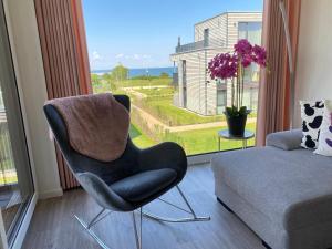 费马恩BeltBlick Fehmarn - moderne Ferienwohnung mit Meerblick und Sauna - Neubau的客厅里有一把椅子和一张沙发,客厅里有一扇窗户。