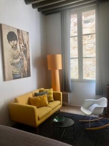 a living room with a yellow couch and a window at Studio Anna centre historique Bordeaux St Pierre in Bordeaux