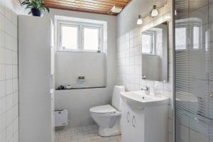 a white bathroom with a toilet and a sink at 4259-Stege-Fabriksgade-14 in Stege +15 photos