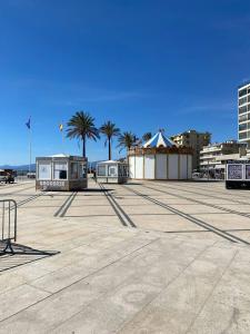 a parking lot with palm trees and a tent at Maison de vacances moderne et pratique : WiFi, clim, parking et cour privée in Canet-en-Roussillon +19 photos