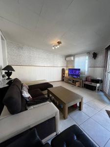 a living room with a couch and a table at Maison de vacances moderne et pratique : WiFi, clim, parking et cour privée in Canet-en-Roussillon