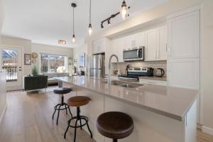 a kitchen with white cabinets and a large island with bar stools at Casa de Luna by Canadian Rockies Vacation Rentals in Canmore