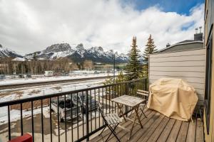 balkon ze stołem i krzesłami oraz pokrytymi śniegiem górami w obiekcie Casa de Luna by Canadian Rockies Vacation Rentals w mieście Canmore