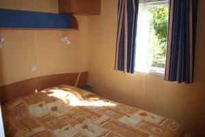 a bedroom with a bed and a window at Camping Le Rebau in Montblanc
