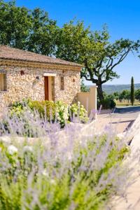 a stone house with purple flowers in front of it at La Bastide Saint Georges & Spa in Forcalquier