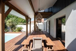 a wooden deck with a bench and a chair at Villa Douceur d'Océane in Biscarrosse