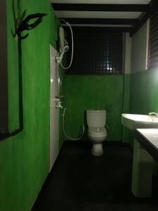 a green bathroom with a toilet and a sink at Sajee Eco Lodge in Sigiriya