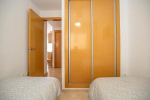 a bedroom with two beds and a wooden closet at JARDINES DEL MAR II Vitamina D todo el año entre playa y montaña in El Borseral +8 photos
