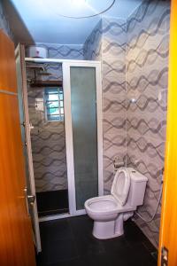 a small bathroom with a toilet and a shower at Buddiez Hotel & Resort in Enugu +96 photos
