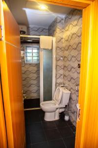 a small bathroom with a toilet in a stall at Buddiez Hotel & Resort in Enugu