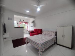 a bedroom with a bed and a red chair at Prainha apto 202 in São Vicente