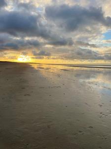 a beach with a cloudy sky and the ocean at Strandhuisje Anna dicht bij de zee in Ouddorp