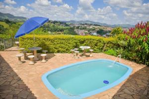 una piscina con sombrilla, mesas y sillas en Vista Linda, en Socorro