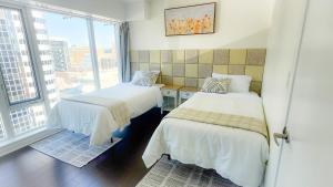 two beds in a room with a large window at Pantages Skyline Suite in Toronto Centre - Free Parking in Toronto
