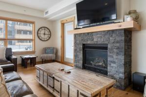 a living room with a fireplace with a flat screen tv at Spring Creek Corner Condo by Canadian Rockies Vacation Rentals in Canmore