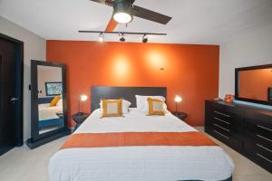 ein Schlafzimmer mit einem großen Bett mit einer orangefarbenen Wand in der Unterkunft ALTABRISA Casa Familiar en Merida in Mérida