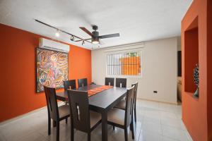 ein Esszimmer mit orangefarbenen Wänden sowie einem schwarzen Tisch und Stühlen in der Unterkunft ALTABRISA Casa Familiar en Merida in Mérida + 7 Fotos