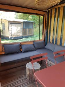 a couch in the back of a tent with a table at Camping Onlycamp du lac de Roybon in Roybon +16 photos