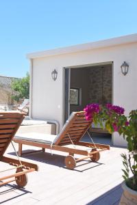 a pair of lounge chairs on a deck with flowers at Village Escape House by CorfuEscapes in Lefkimmi