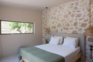 a bedroom with a bed with a stone wall at Village Escape House by CorfuEscapes in Lefkimmi +39 photos