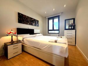 a bedroom with a large white bed and a lamp at Playa de los Locos con Garaje Recién Reformado!! in Suances