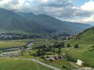 een klein stadje op een heuvel met bergen op de achtergrond bij Gagma Chalets Kazbegi in Kazbegi