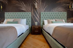 a bedroom with two beds and a wall with plants at Palazzo De La Sengle Boutique Hotel in Senglea