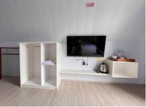 a white room with a tv on a wall at Glamping Sarangan in Sarangan