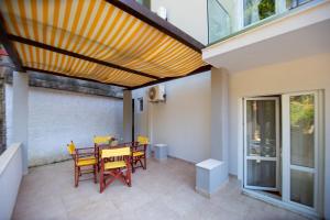 a patio with a table and chairs under awning at ACIKA apartments in Rafailovici
