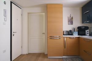 a kitchen with wooden cabinets and a door with a microwave at Il Gabbiano Blu in Chioggia