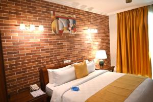 a bedroom with a bed with a brick wall at Grand Hôtel City - Akwa in Douala