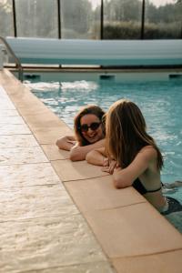 two women laying in a swimming pool at Les Roulottes & Cottages du Moulin in Chenillé-Changé +14 photos